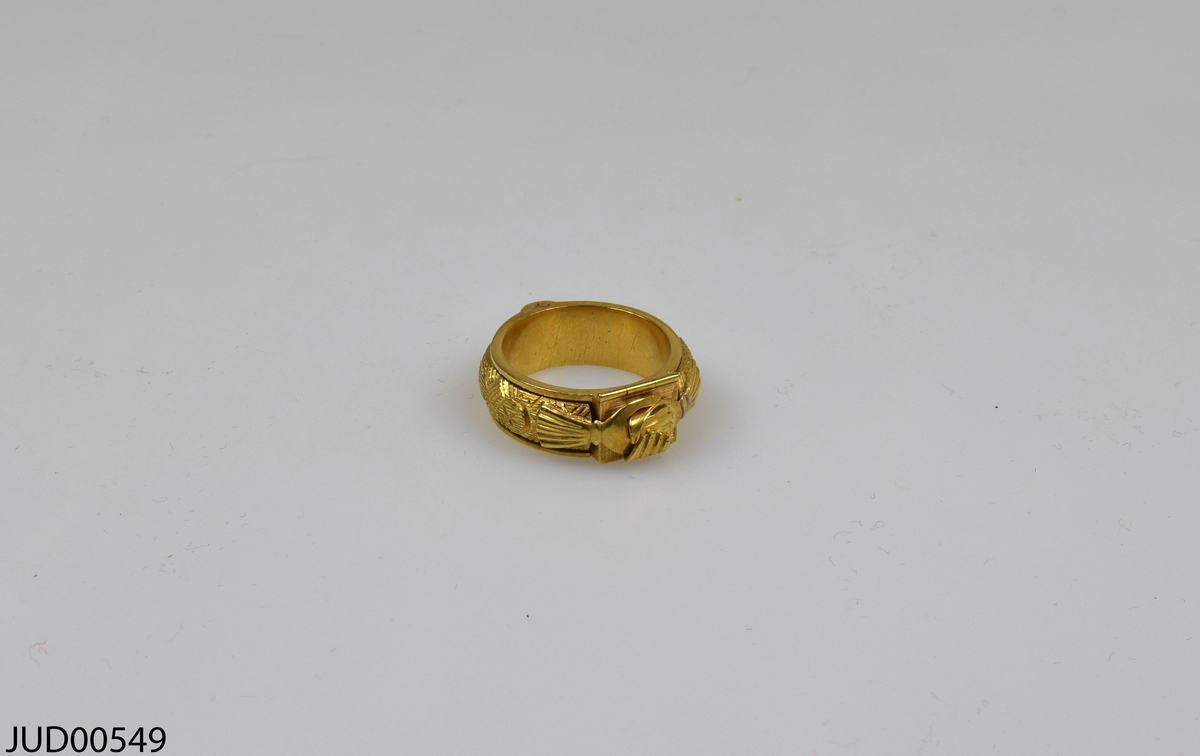Guldpläterad silverring, med två händer hand i hand som går att öppna. Under finns en lucka som går att öppna, och inuti finns blå sten med hebreisk text i.