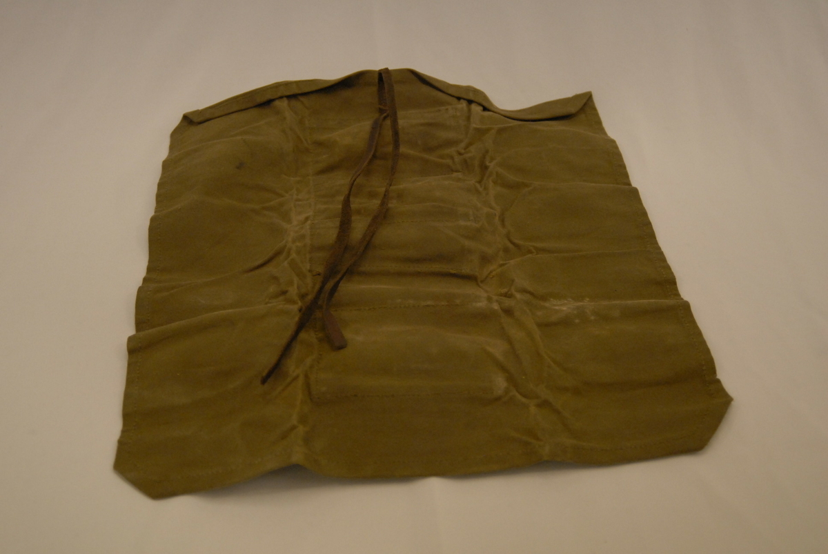 Militærgrønt etui av tøy med fire små gjenstandar i lommene.