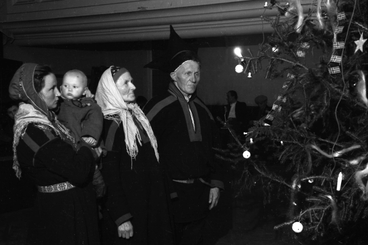 Det er julaften 1944. Fire personer står med alvorlige miner ved et juletre som er pyntet med kuler, lys og norskeflagg. Det eldre paret til høyre er Berit og Ole Eliassen. En yngre kvinne ved siden av holder sitt barn. De er kledd etter samisk folkeskikk. De er tvangsevakuerte fra Porsanger og befinner seg i Metodistkirkenen i Trondheim der de er innlosjert.