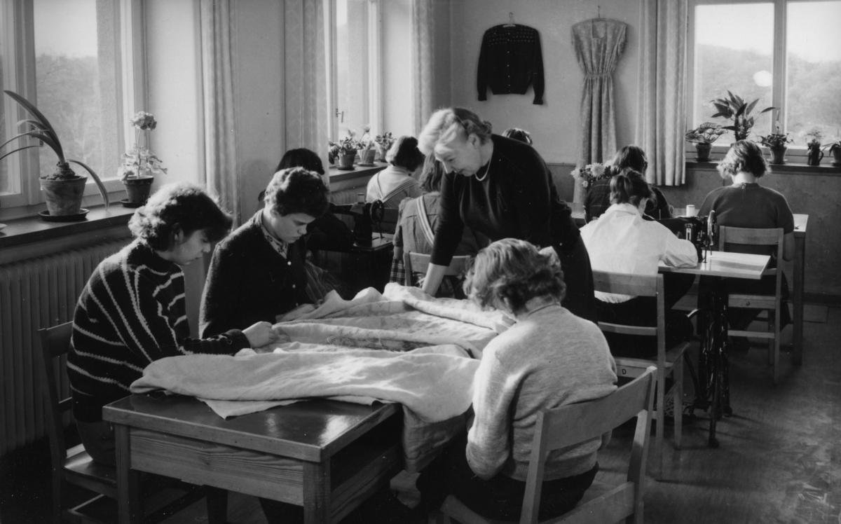 Vykort från förskolan i Stretereds skolhem (nuvarande Videgården), 1950-tal. Lärare Märta Blomkvist med kvinnliga elever i syslöjden på våningsplan 1 (ovanpå vävsalen). Relaterade motiv: A2809 - A2815.