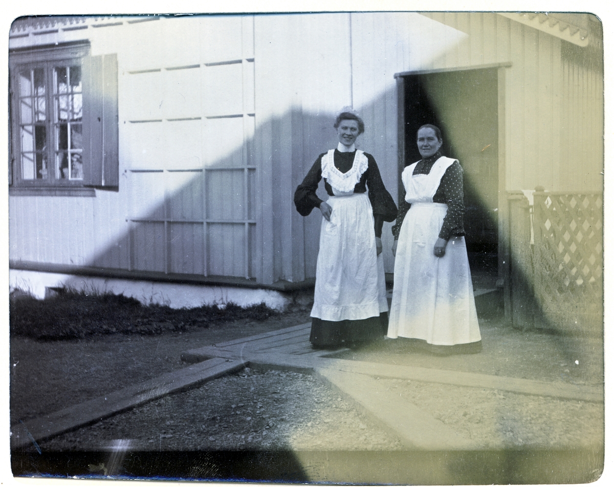 To tjenestepiker som vartet opp nygifte Nini og Westye Egeberg under oppholdet på Egeberg-familiens Strøm gård, antagelig Vestre Strøm gård i Rælingen. Kvinnen til høyre heter Lina. Fotografert i september 1904.