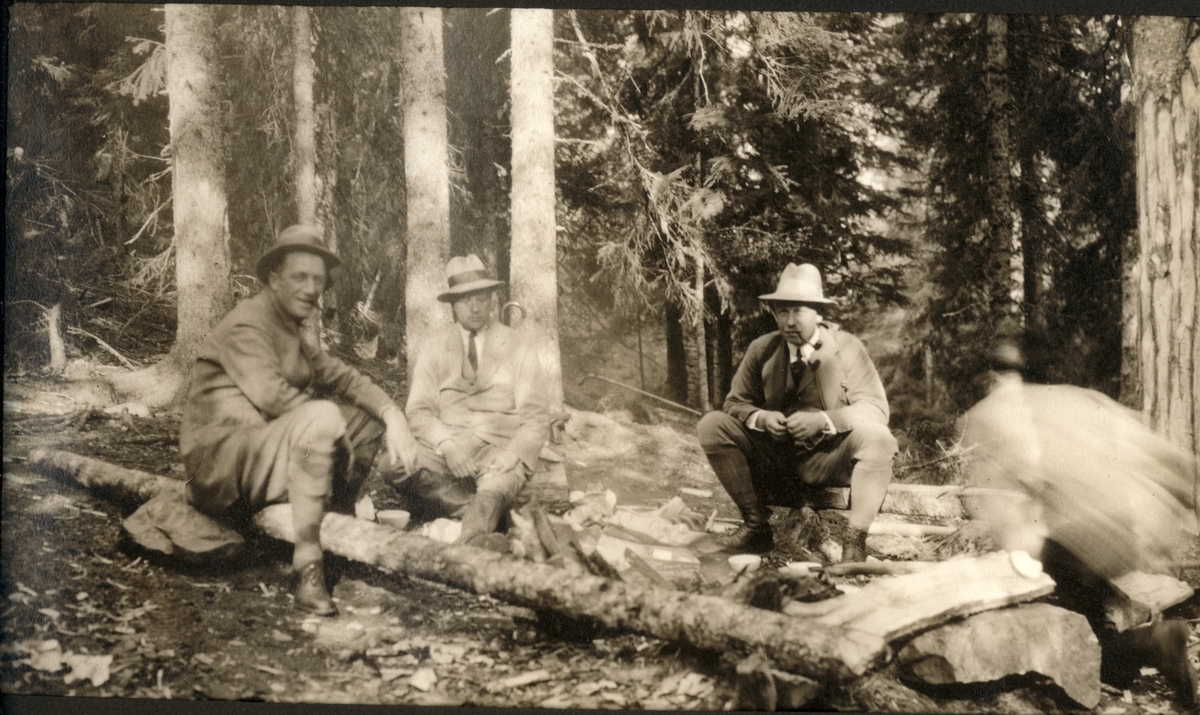 Einar W. Egeberg, Sir Edward Chichester,  og Westye Egeberg sitter på trestammer i et skogholt. Fotografert 1922.