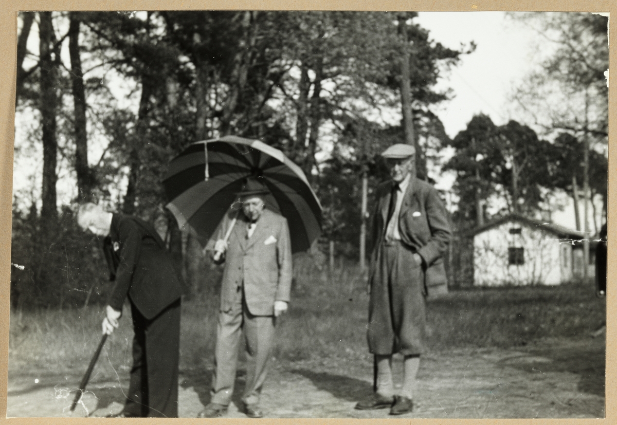 Tre menn fordriver tiden med golf mens de venter på flere deltakere. Til venstre Westye Parr Egeberg og til høyre Aksel Hansen. I midten August Walle-Hansen med parasoll/paraply. Antagelig fotografert i nærheten av Dejefors, Sverige, mens skiklubben Fram var på besøk der i mai 1954.