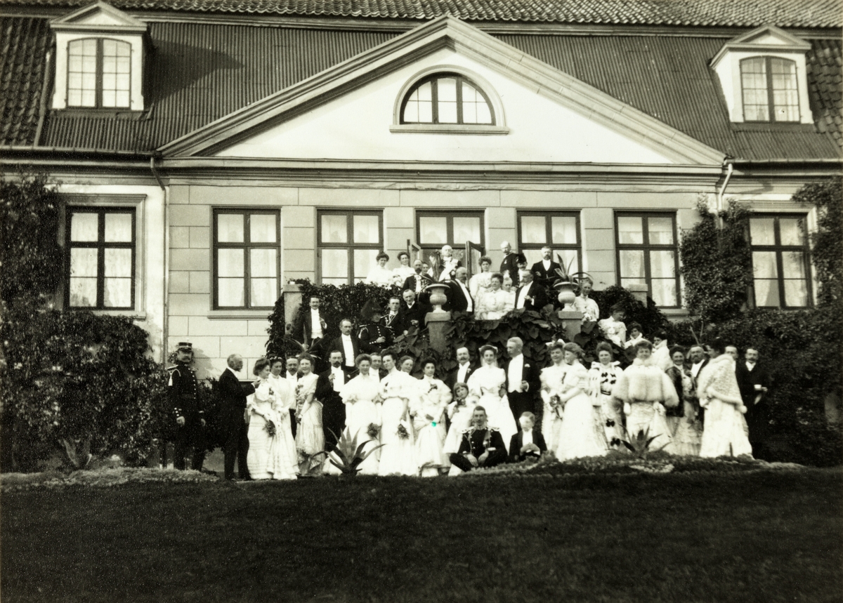 Brudeparet Nini, f. Wedel Jarlsberg, og Westye Parr Egeberg sammen med familie og andre bryllupsgjester foran hovedbygningen på Bogstad gård. Fotografert 17. september 1904.