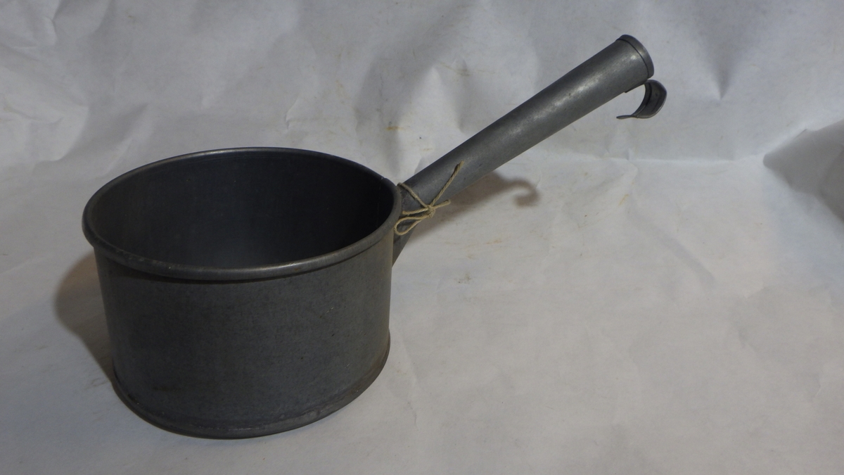 Form: Sylinderisk kopp med rørformet håndtak med liten opphengskrok ytterst
