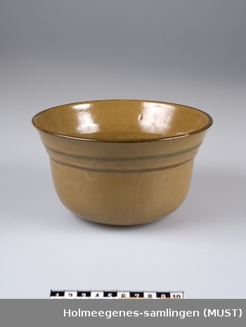 Brun potteskjuler i keramikk med to riller med grønn og brunn stripe langs rillen. Brun kant.