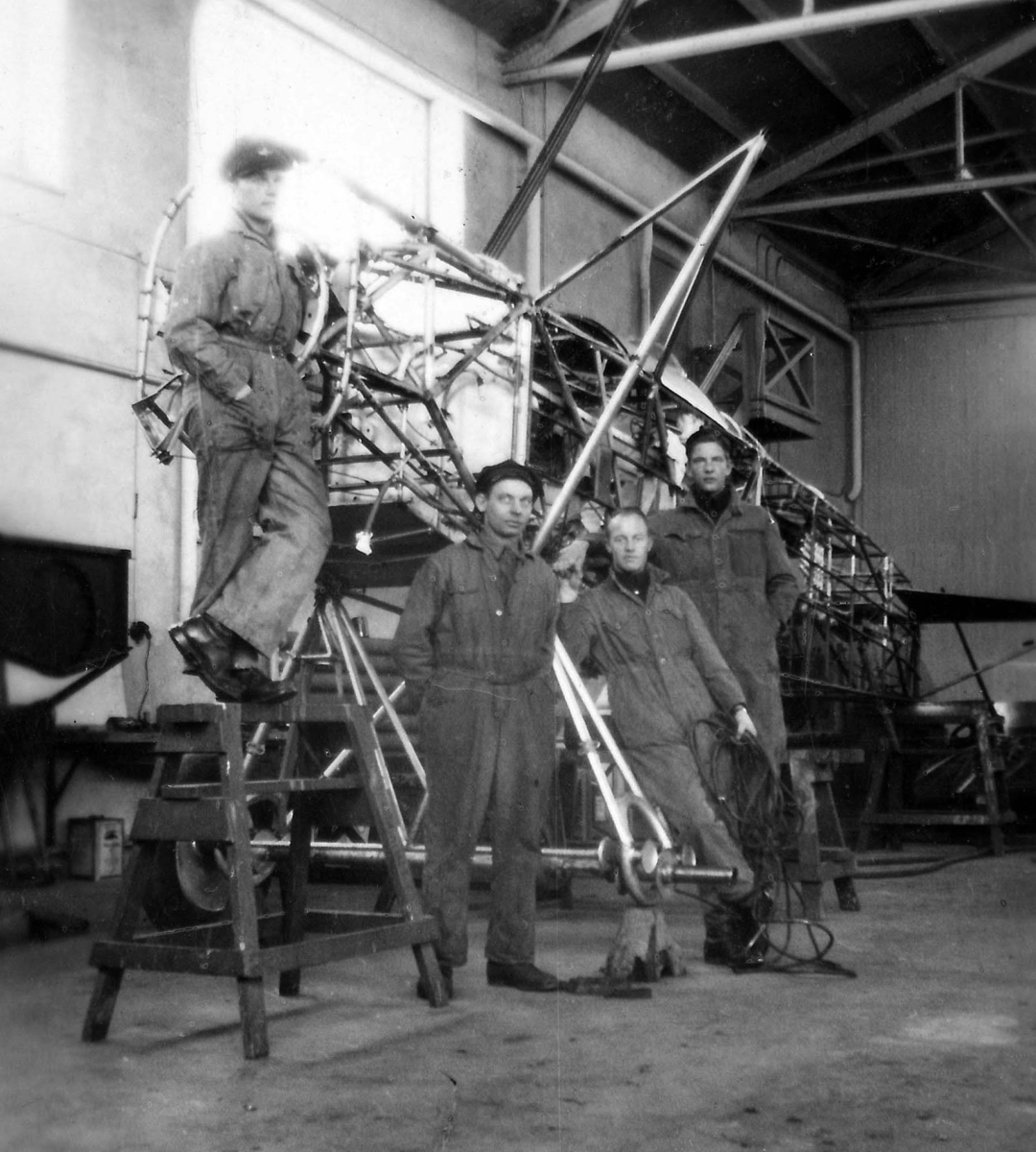Fyra mekaniker står uppställda vid stomme till ett flygplan S 6 i en hangar. 1930-tal.