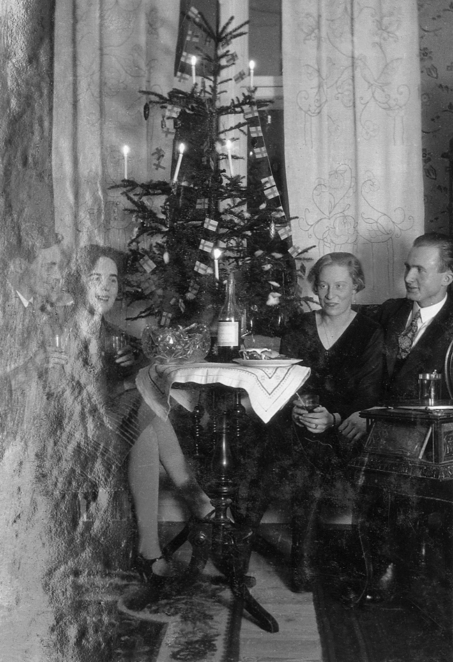 Två par sitter vid en julgran. 
Under fotot text: "Julen 1929".