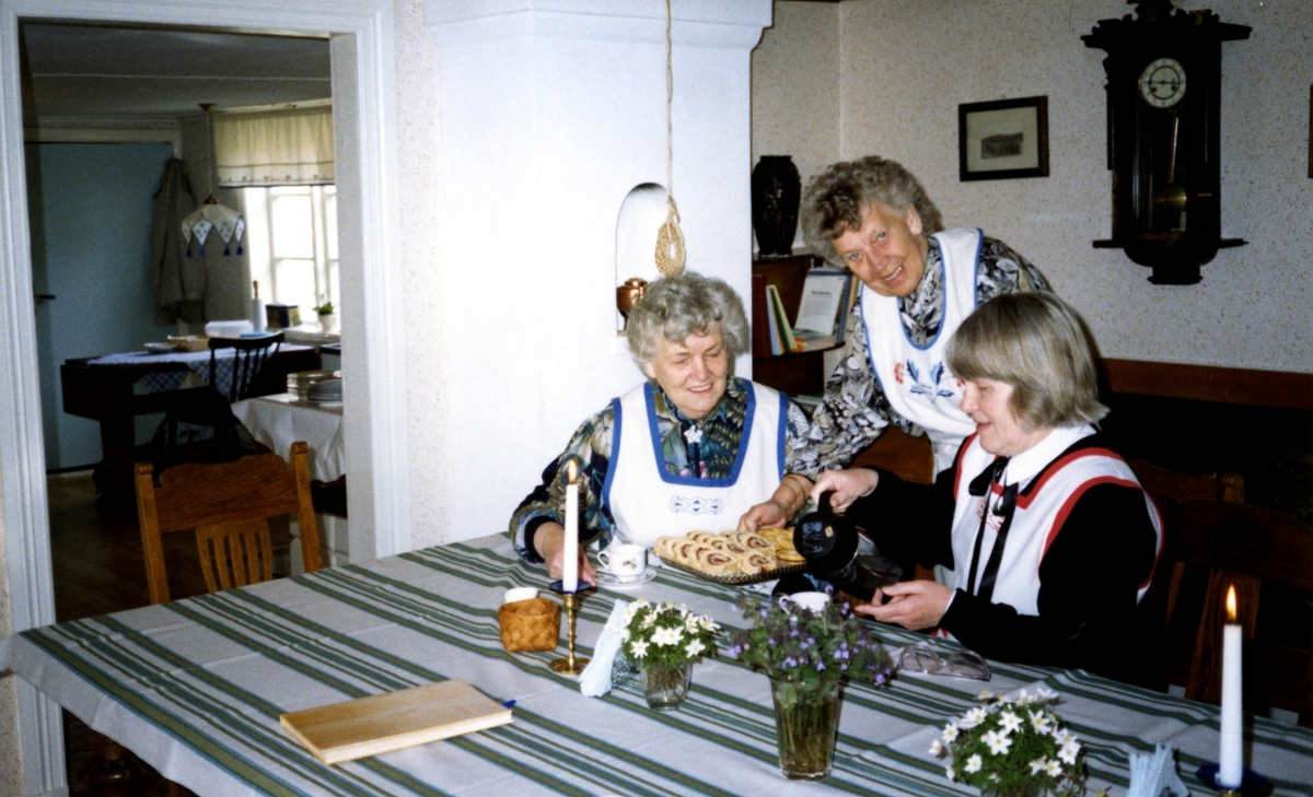 Tre kvinnor iklädda förkläde, Hembygdsgården Långåker 1:3 1980-tal. Från vänster: Inga-Maj Carlsson (1920 - 1999, Vommedal), Stina Svensson (1912 - 2001, Vommedal) och Emy Johansson (Torrekulla).