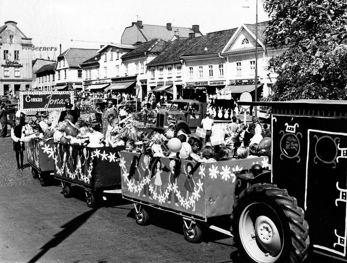 Barnens dag 1960. En traktor drar vagnar med barn i paraden förbi folksamling på torget.