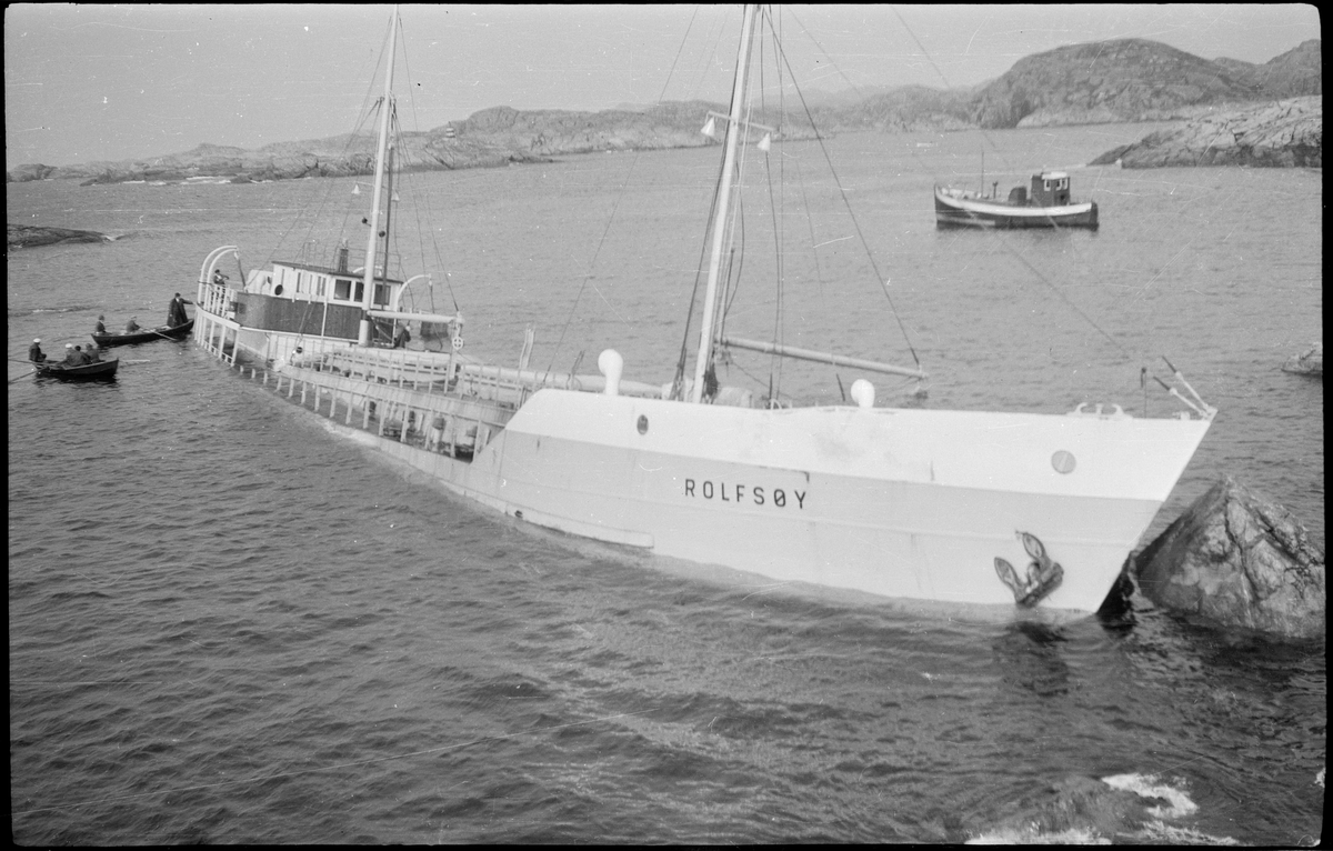 Lasteskipet "Rolfsøy" på grunn utenfor Egersund. Flere mindre båter er uten for å se og forankre skipet.