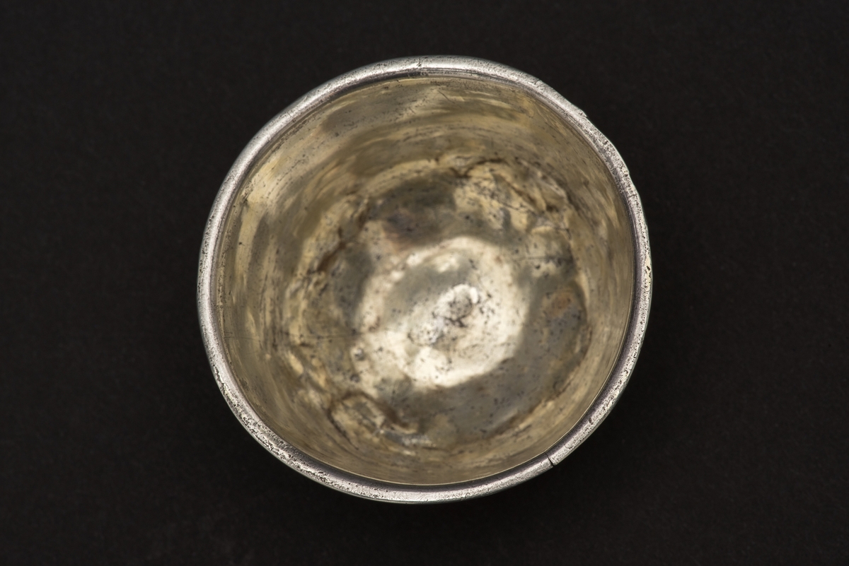 Rund supkopp med nedvikt mynningskant av silver. 
Koppen är förgylld inuti samt över mynningsbården. Bården består av en sicksackbård och därunder ett slätt band.