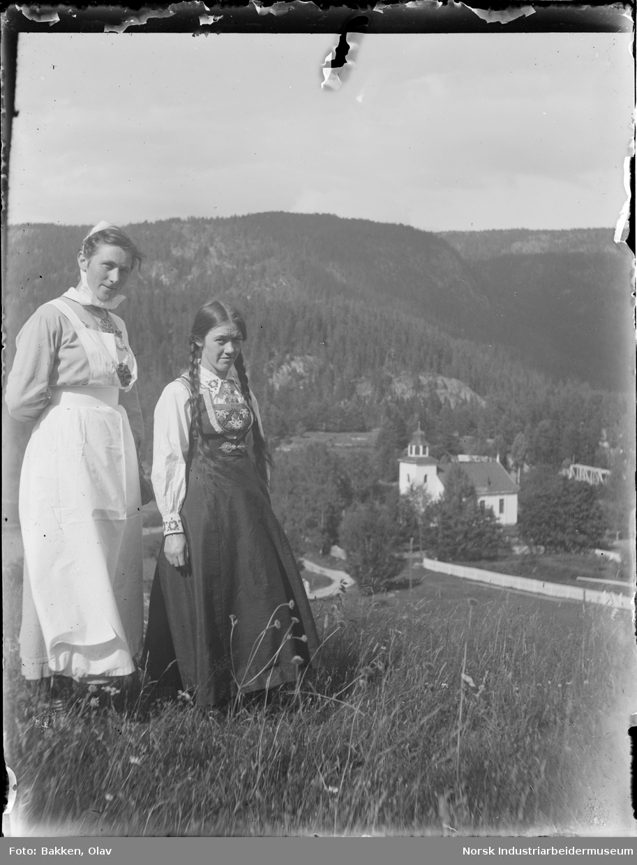 To kvinner stående på gressbakke. Gransherad Kirke i bakgrunnen.
