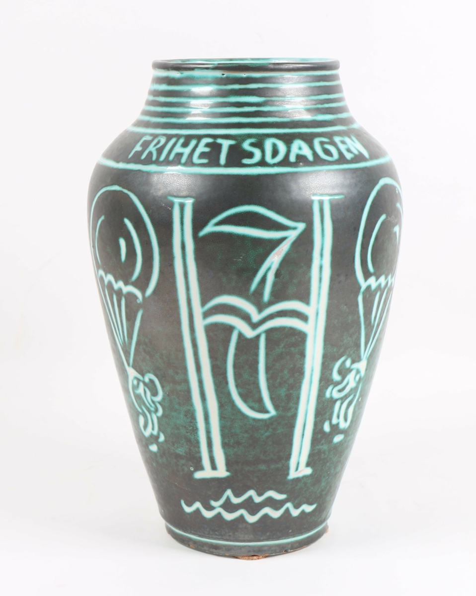 Vase i grønn keramikk med hvit dekor/skrift.