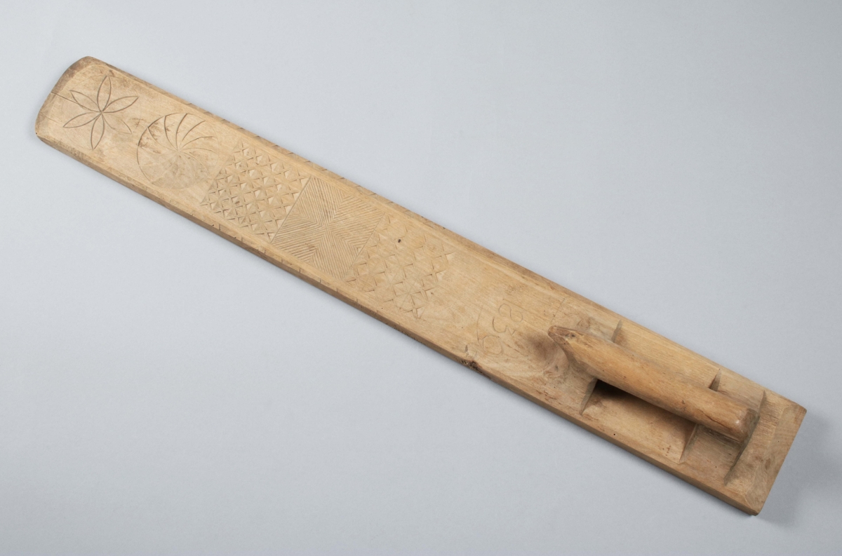 Mangelbräde i ofärgad björk. Handtaget skuret i ett med brädet; degenererad hästform. Dekor i form av skuren rosett, virvelhjul och rutmönster. Fasade, uddade kanter. Framför handtaget skuret årtal: "1839". (Gunnar Blomgren)

Mangelbräde eller kavelbräde är ett redskap av trä som använts för mangling av textilier. Mangelbrädet användes tillsammans med en kavel, en slät rulle av trä. Den textil som skulle manglas, rullades upp på kaveln, på ett bord eller annat slätt underlag. Under hårt tryck, rullades kaveln med hjälp av mangelbrädet, fram och tillbaka över bordet. (Wikipedia)