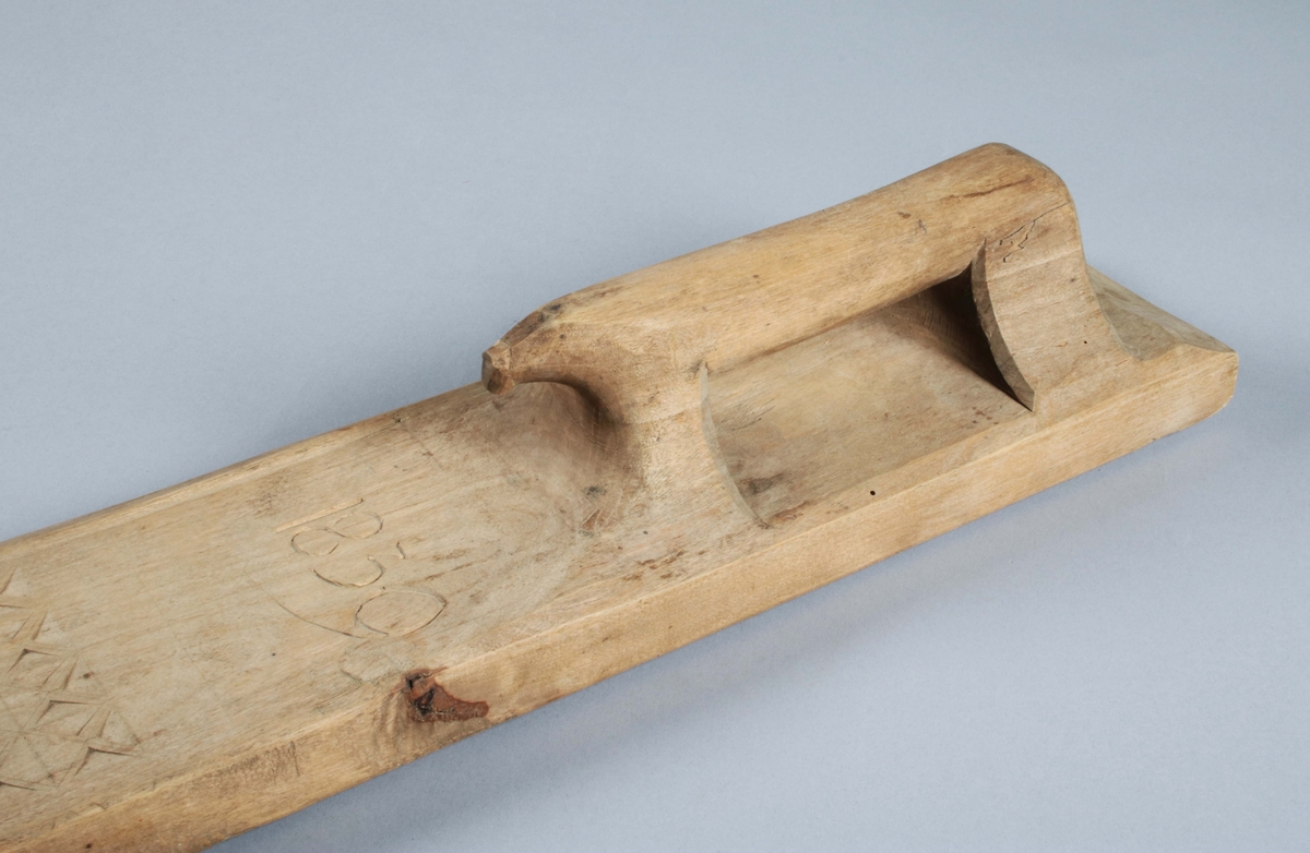 Mangelbräde i ofärgad björk. Handtaget skuret i ett med brädet; degenererad hästform. Dekor i form av skuren rosett, virvelhjul och rutmönster. Fasade, uddade kanter. Framför handtaget skuret årtal: "1839". (Gunnar Blomgren)

Mangelbräde eller kavelbräde är ett redskap av trä som använts för mangling av textilier. Mangelbrädet användes tillsammans med en kavel, en slät rulle av trä. Den textil som skulle manglas, rullades upp på kaveln, på ett bord eller annat slätt underlag. Under hårt tryck, rullades kaveln med hjälp av mangelbrädet, fram och tillbaka över bordet. (Wikipedia)