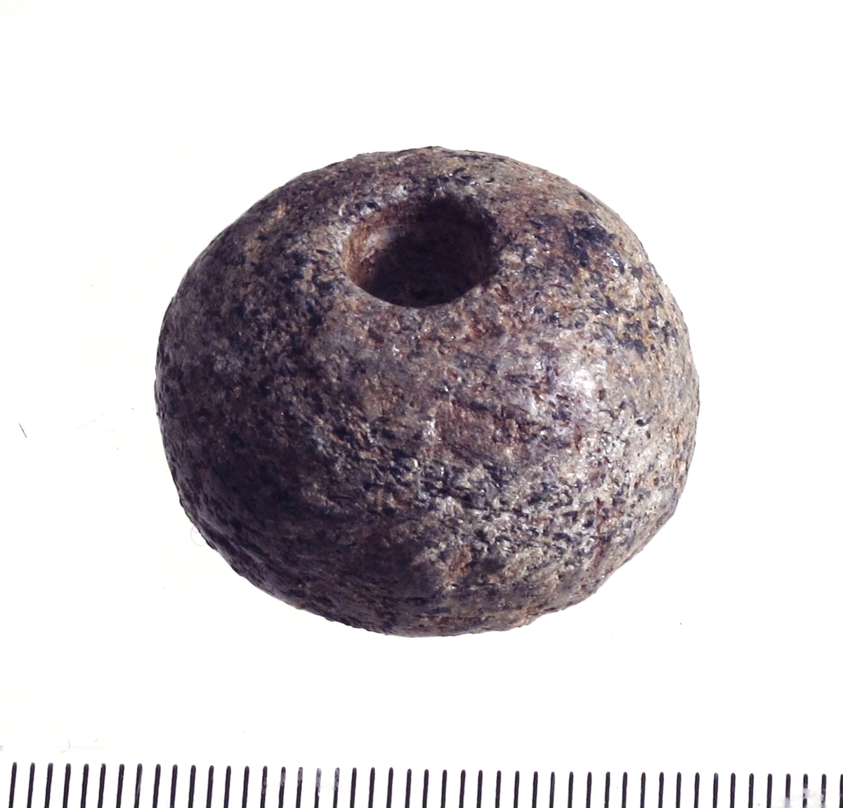 Lite spinnehjul av kleberstein, av type som Vikingetidens Redskaper, fig. 164, men noe mindre. - Tverrmål 3 cm.