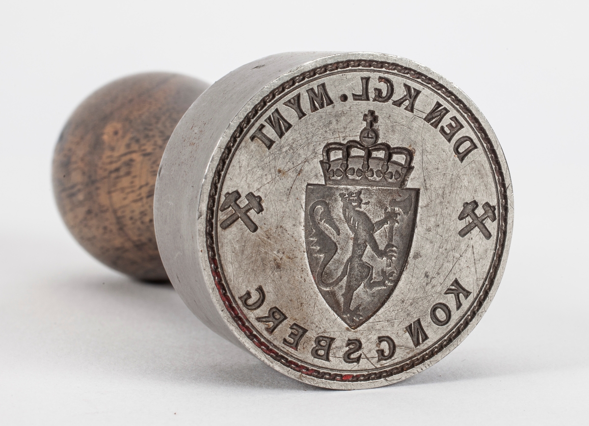 Norges riksvåpen, løve med øks og krone på ett skjold med krone over. På hver side er symbolet med hammer og feisel i kryss.