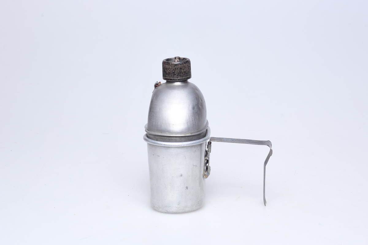 Feltflaske med kar (kopp/ matskål) og futeral, for bruk i felten ved bespisning. Flasken har skrukork med metallenke. Flasken er plassert oppe i karet, og karet har et håndtak. Flasken er merket U.S. Vollrath 1944. Karet er merket U.S. E.A. Co. 1943. 
Flaskens futeral har US oppheng og 2 trykknapper. Futeralet er grønt og er festet til beltet registrert på TM-12210.
I bunnen på karet er det risset inn en ørn og et navn over; Michael P. Somen (?).