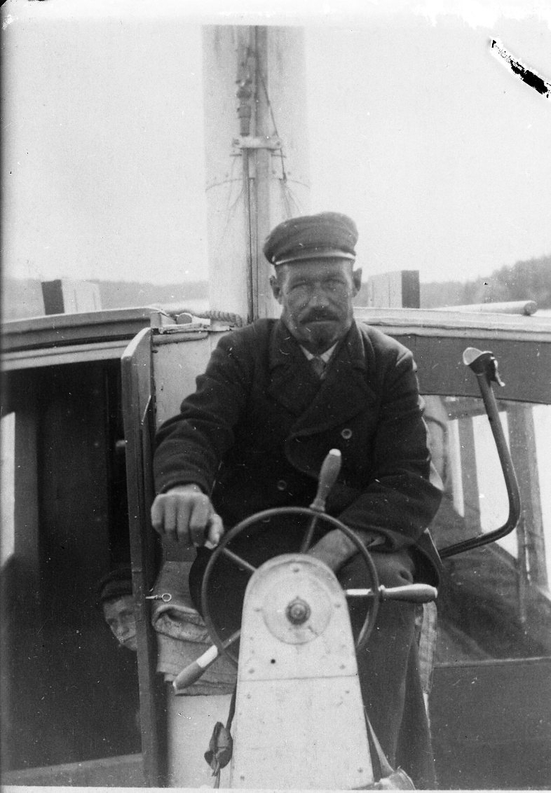 En man sitter vid en båts rorkult.