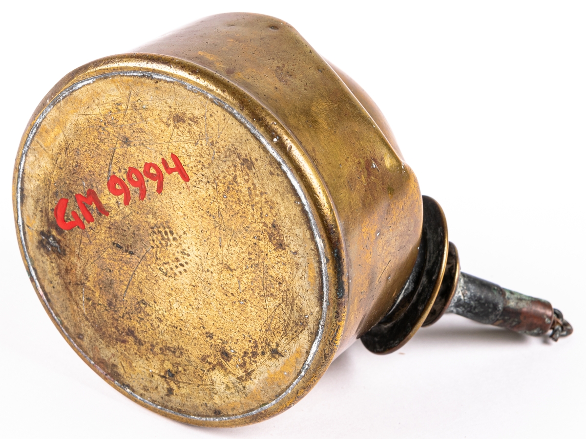 Rovoljelampa. Gaslampa, rund dosa av koppar, med kort brännare med veke snett åt sidan. Har använts av en skomakare.