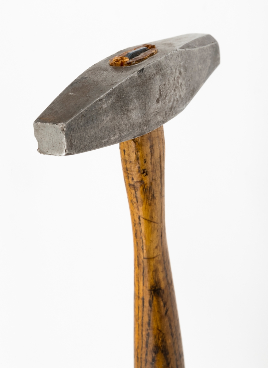 Hammer brukt til retting av sagblad, særlig til tømmersvanser.  Hammeren består av et hammerhode (penn) og et skaft av treverk. Hammerhodet har et ovalt skafthull (cirka 2 cm langt). Skaftet har et ovalt tverrsnitt i håndtaksdelen. Hammerhodet har tilnærmet lik utforming i begge ender som munner ut i en kvadratisk slagflate cirka 10 x 10 mm i ene enden og en åttekantete slagflate i den andre enden, cirka 16 x 16 mm. Det er satt inn en jernkile i skaftenden som munner ut i hammerhodets skafthull. Jernkilen utvider skaftenden slik at skaftet sitter godt i skafthullet.
Det er rester av rød maling på skaftenden og litt på siden av skaftet.
