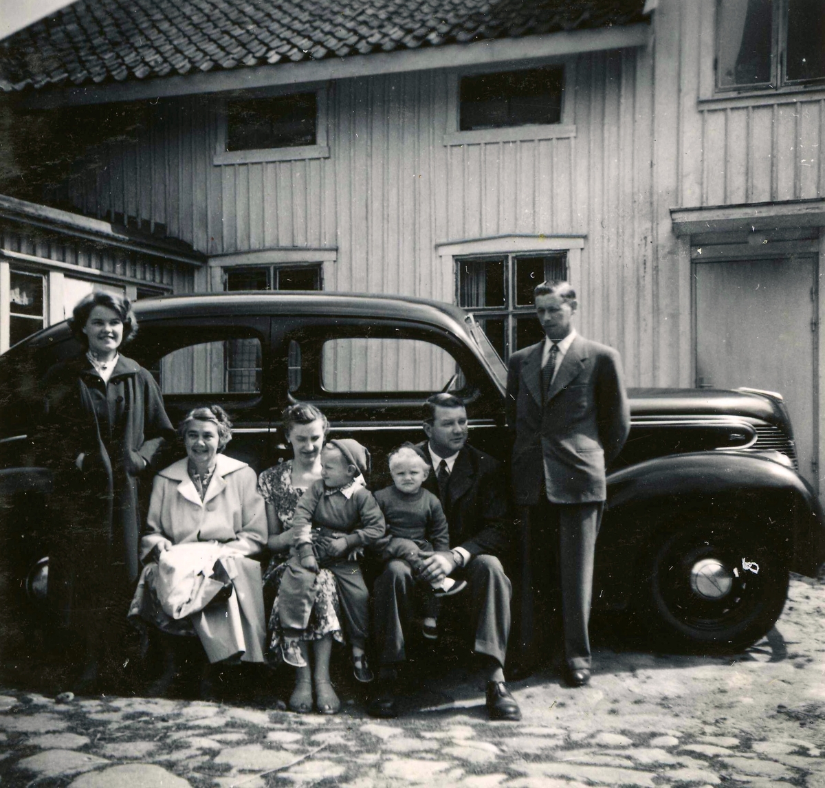 Sju personer står samlade framför en bil vid Ekans gård, Ekan 1:1 år 1953. Från vänster: 1. Eva Svensson (född 1936, gift Johansson, dotter till nr 7). 2. Elsa Svensson (1901 - 1990, gift med nr 7), gårdens ägare. 3. Edit Melin (1918 - 2000), Kyrkbacken. 4. sonen Lars-Åke Melin (född 1948), Kyrkbacken. 5. sonen Sven-Olof Melin (född 1951), Kyrkbacken. 6. Åke Melin (1913 - 1970), Kyrkbacken. 7. Rolf Svensson (född i Släp 1909, avliden i Kållered 1989), gårdens ägare och brukare.
