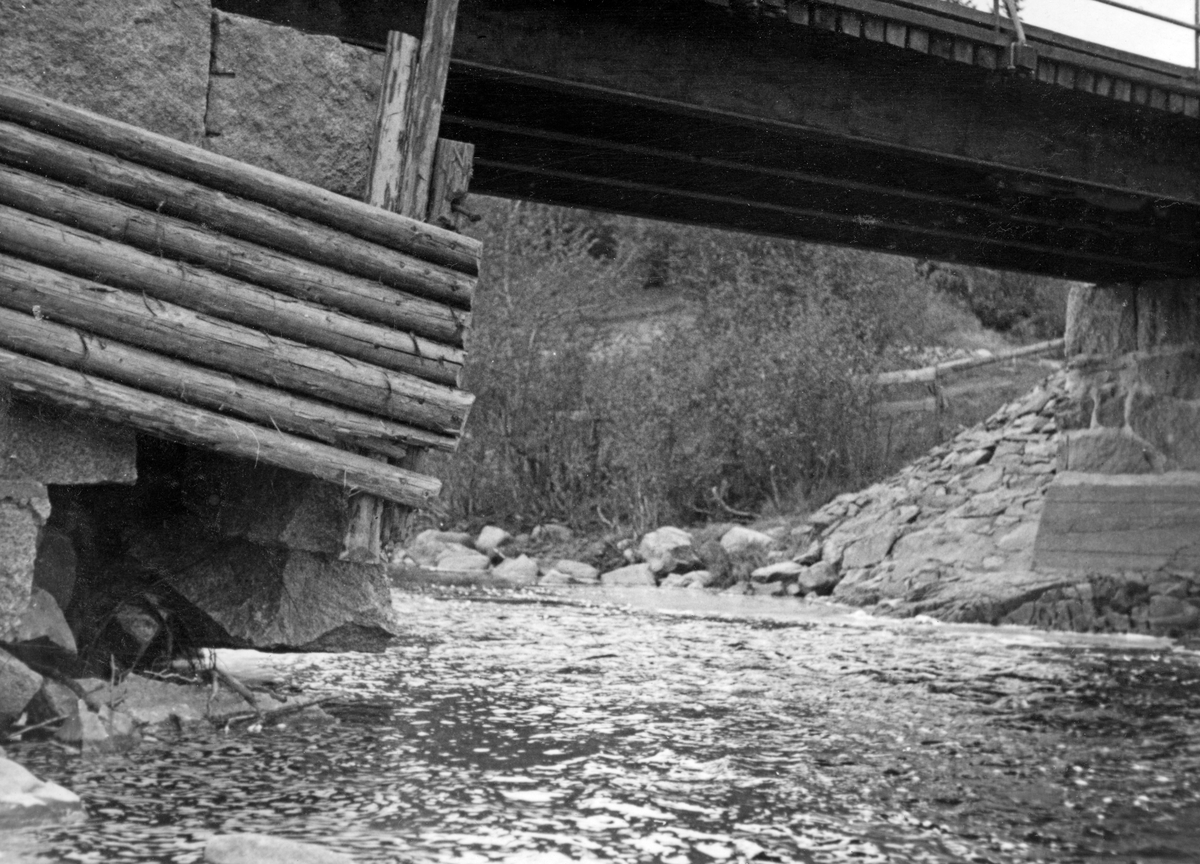 Knapper bru over elva Juråa i Nord-Odal i Hedmark. Dette fotografiet ble tatt i 1936, antakelig for å dokumentere en skade på brukaret på østre elvebredd. Det var murt av kvadret naturstein, men et par av steinene nederst i murverket, på hjørnet på motstrøms side, hadde rast ut. Sida av brukaret var forblendet med en lem, lagd av granne rundstokker, antakelig montert for å avvise fløtingstømmer som kunne legge seg mot brukaret i fløtingssesongen, da vannføringa i Jura brukte å være langt større enn den var da dette fotografiet ble tatt. Elveskråningen ved sida av brukaret var plastret med steinheller, som skulle forebygge erosjonsskader. Knapper bru var ei bjelkebru, med H-bjelker av jern som bar en vegbane av tre. Langs kjørebanens ytterkanter var det montert et rekkverk av jernrør.