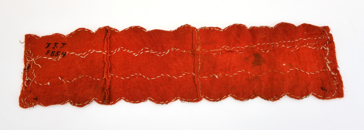 Bredt rødt ullbånd med påsydde sølvkniplinger i 3 rader. Bunnstoffet er syd sammen av flere små deler. Reparert i endene. Brukt til dekor på brudepikevalk.