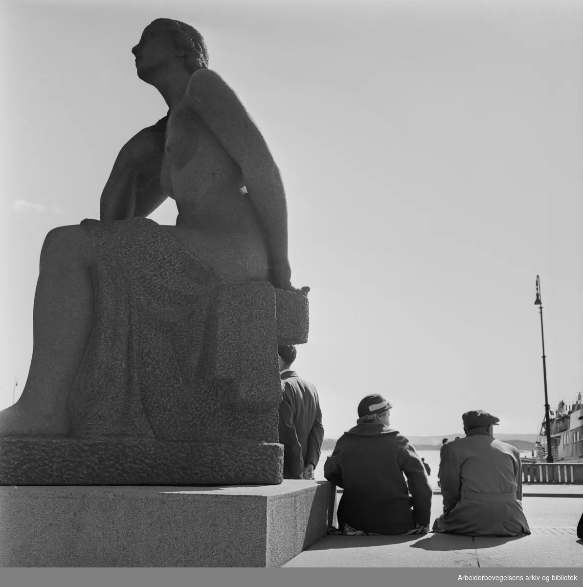 Vårstemning på Rådhusplassen i Oslo. Emil Lies skulptur av sittende kvinne, reist 1954-58. 24. April 1962.