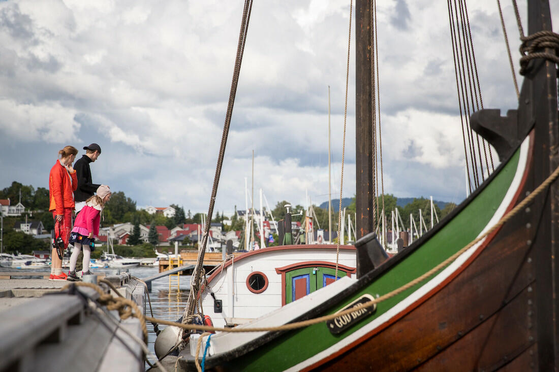 Kvinne, mann og barn står på museumsbryggen utenfor Oslofjordmuseet. De ser på båten "God bør". (Foto/Photo)