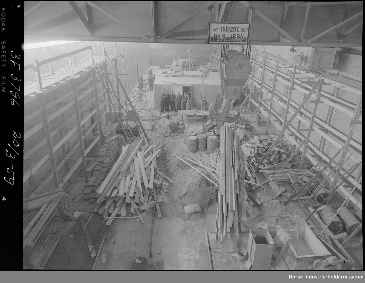 Svælgfos 3 (Svelgfoss 3). Maskinhallen under bygging. Arbeidsmenn stående på gulvet i maskinhallen. Fotografi tatt fra krana i taket. Kranas krok henger ned.