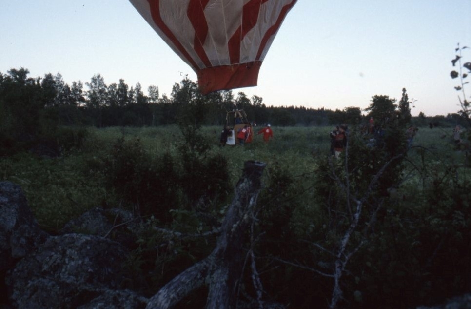 Flera personer på ett fält samlade kring en röd och vit luftballong.