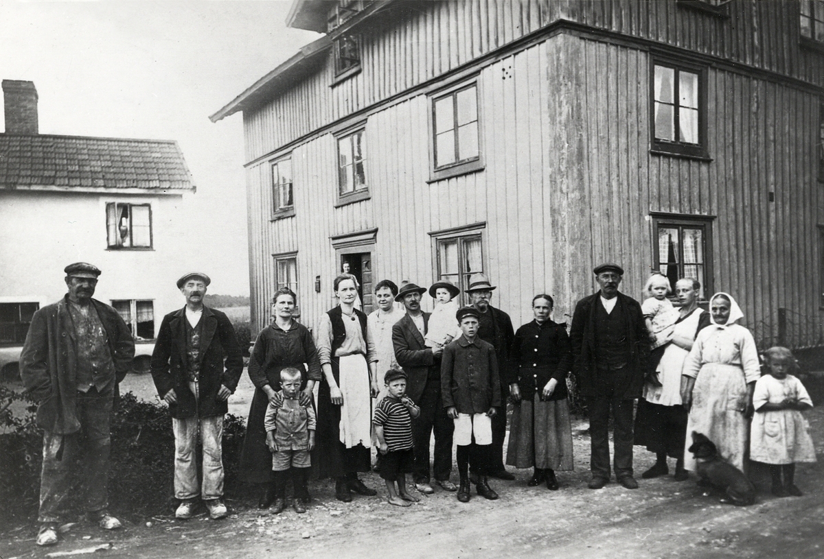 En grupp människor har samlats för fotografen utanför fastigheten Lidboholm 29, Gamla Norr, Växjö. 
I bakgrunden syns fastigheten Hamplyckan.