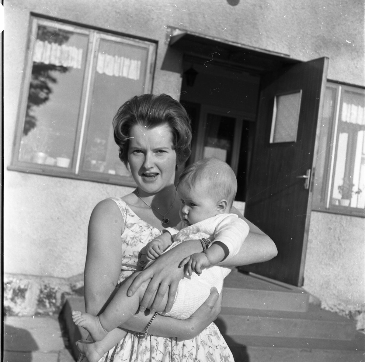 En kvinna håller en bebis i famnen.
