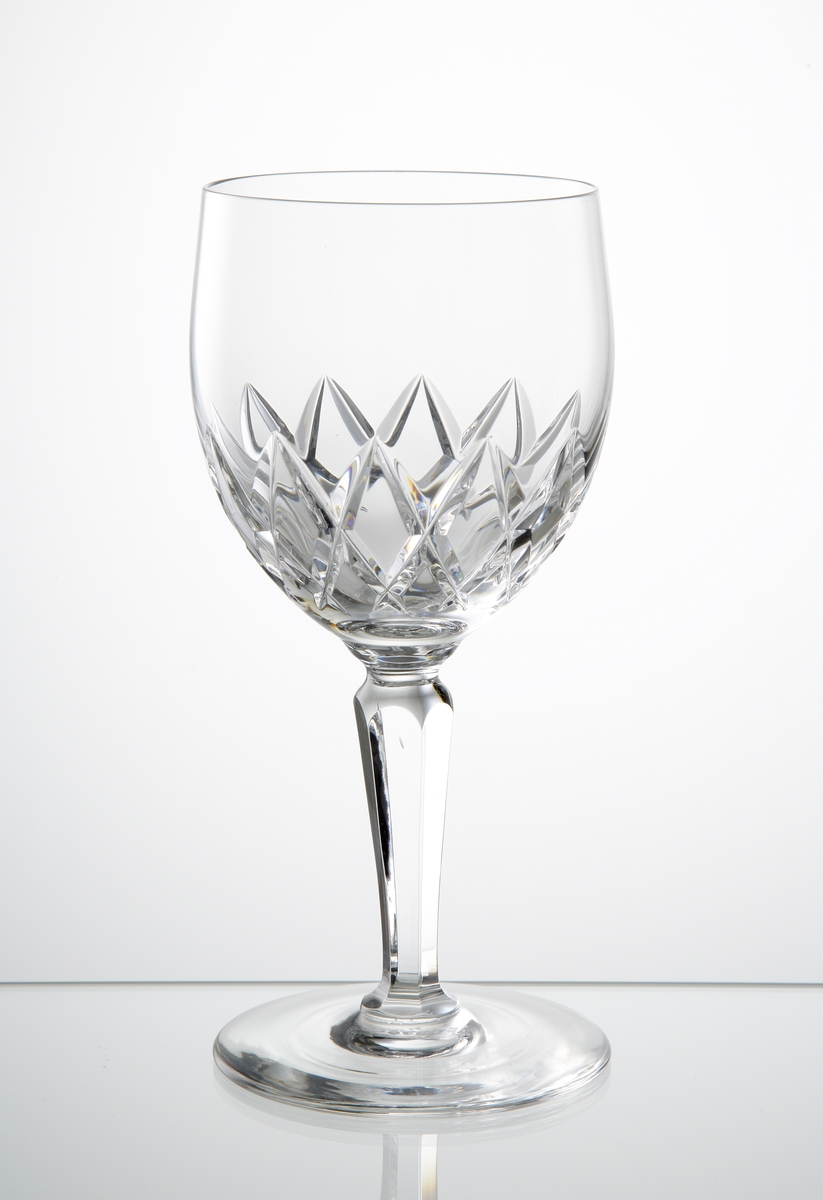 Design: Ingeborg Lundin.
Ölglas (goblet), närmast klotformad kupa med skärslipad dekor på kupans nedre del. Fasettslipat balusterben på slät fot.