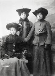 Gruppeportrett av tre  ukjente damer med hatt og kåpe, visit