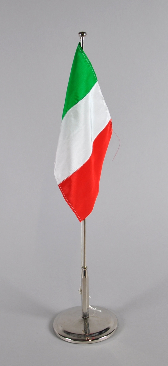 Italiensk bordflagg på liten stang. Tre vertikale striper, grønn innerst mot stanga, hvit på midten og rød ytterst.