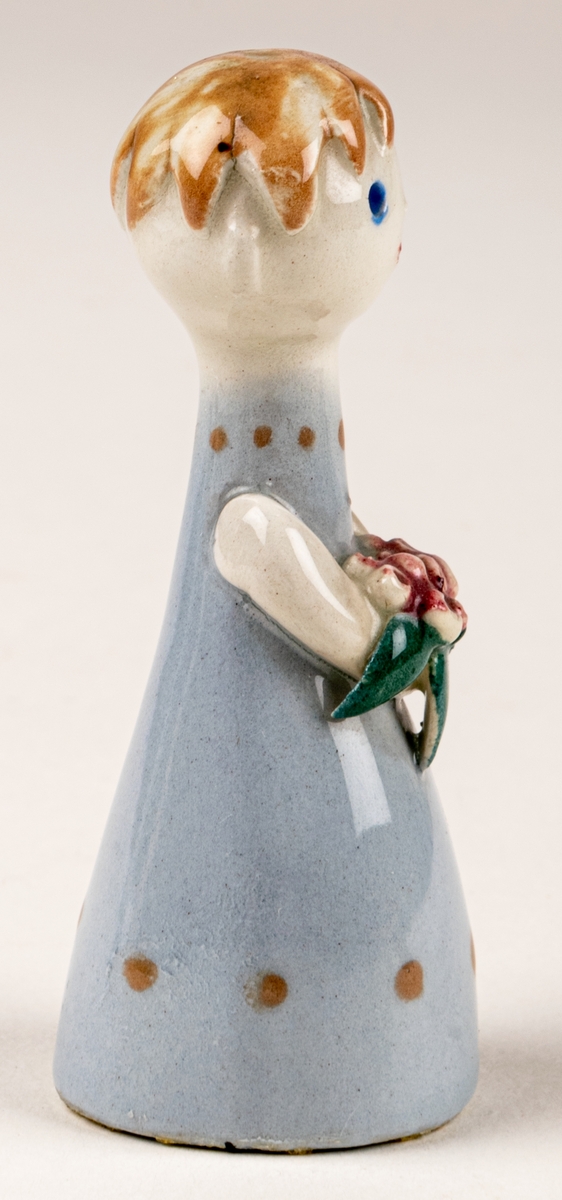 Brudtärna till figuringrupp Brudfölje. Tärnan har ljust hår och ljusblå klänning. Formgiven av Dorothy Clough 1955, Gefle Porslinsfabrik.