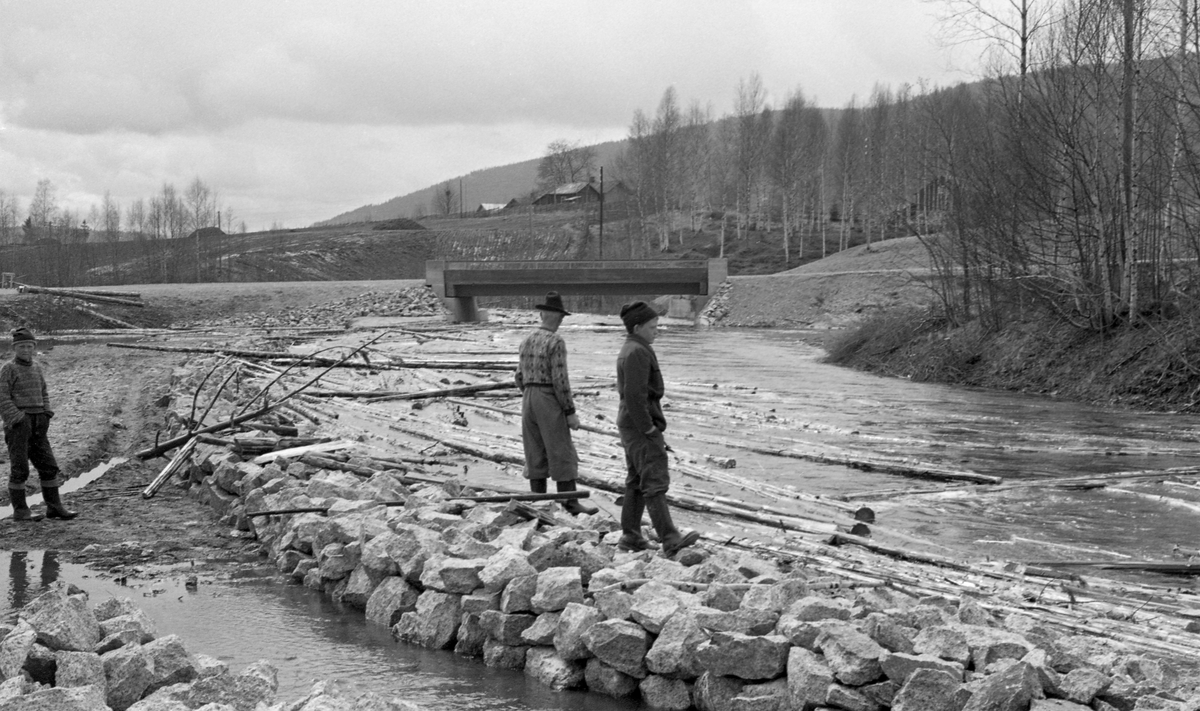 Tannåa, Nord-Odal, Hedmark etter omlegging og steinsetting. Tømmer i elva. Tre personer ved Bergstuen Bru.