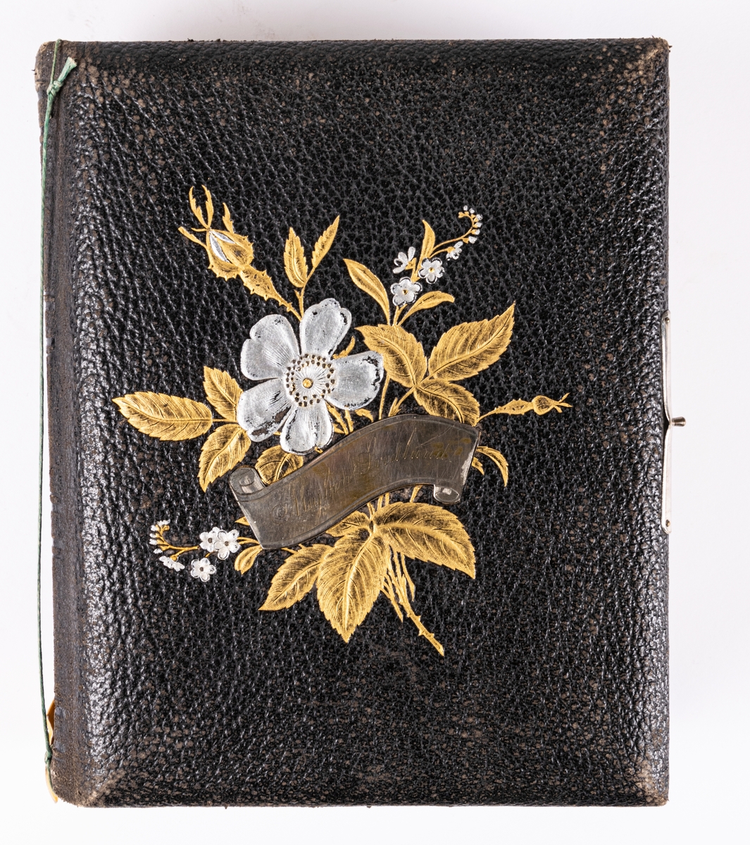 Fotoalbum, svart läder. Dekoration: blombukett med förgyllda blad och försilvrade blommor och namnskylt Majken Svedlund.