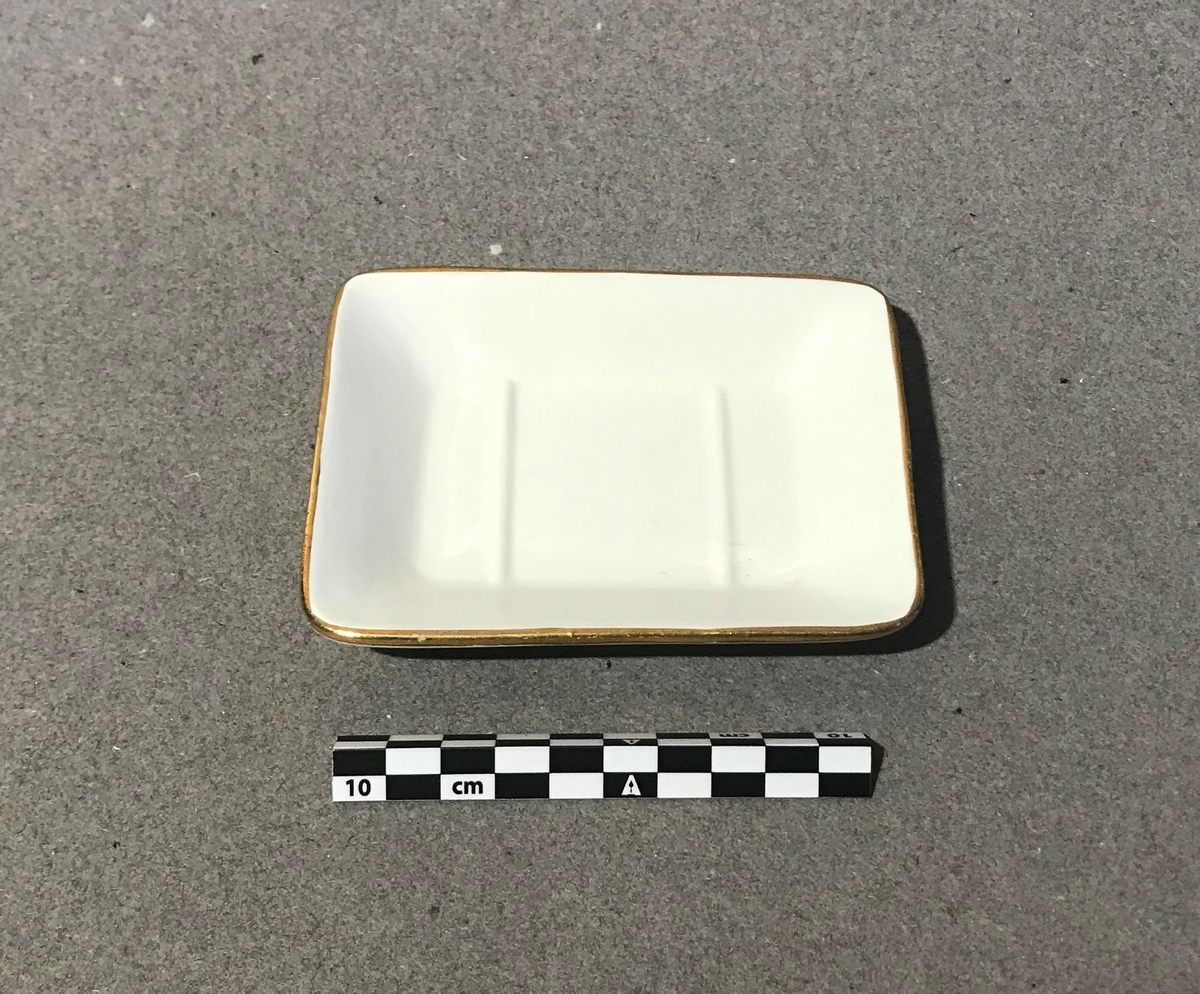 En firkantet, hvit såpekopp med gullkant