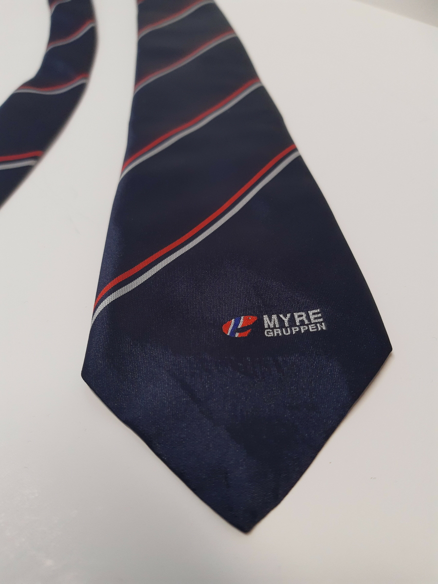Blått slips med røde og hvite striper og logoen til Myregruppen
