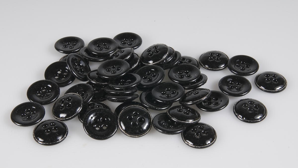 Ett 40-tal svarta fyrhåliga knappar. Förvarades i ask UM17903a.