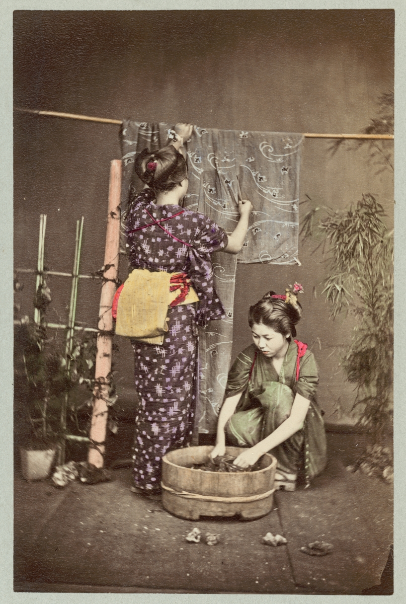 Bilden visar två japanska kvinnor som tvättar och torka kläder. Sceneriet är arrangerat för fotografering i en fotoateljé.