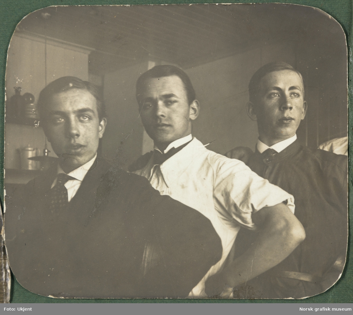 Tre unge menn i arbeidsfrakker, skjorte og slips.