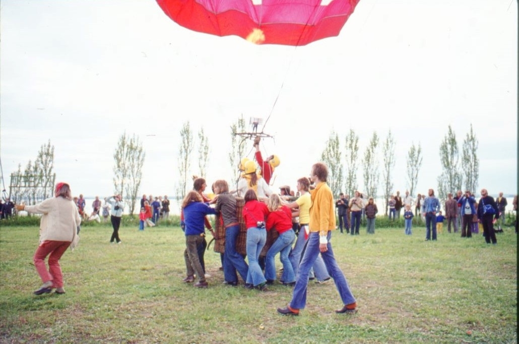 Ett flertal personer håller i en ballongkorg vars ballong är på väg att lyfta.