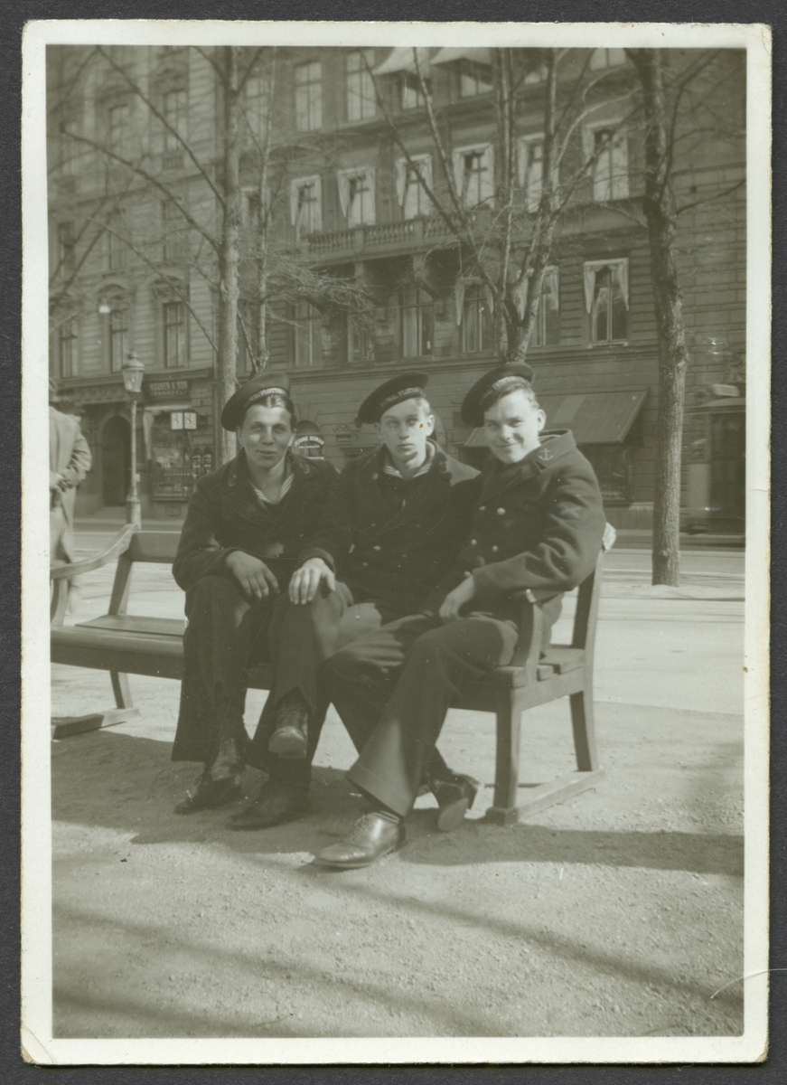 Bilden visar tre sjömän som sitter på en bänk i Kungsträdgården under en utflykt i staden.