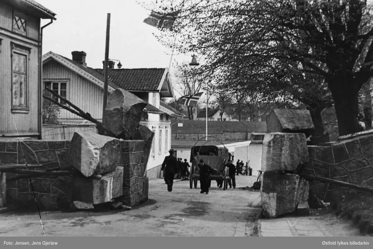 Opptak fra frigjøringsdagene i Fredrikstad mai 1945. Ferjestedsveien ned mot fergestedet. Gamlebyen i bakgrunnen. Vogn dras med håndmakt. Tekst på stein til høyre : Radfahren Verboten.