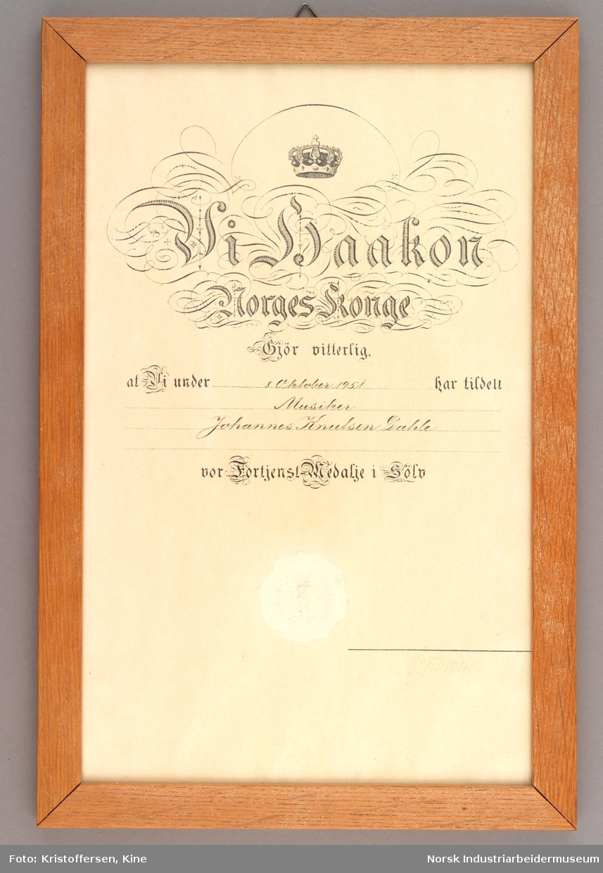 Innrammet diplom av kongens fortjenstmedalje i sølv tildelt spelemannen Johannes Dahle.